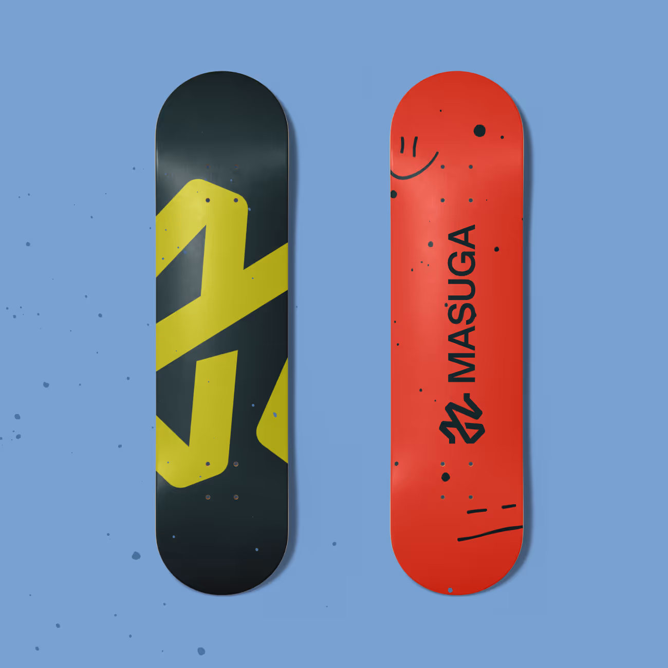 Two snowboards on a blue background, one black with a yellow abstract design, the other red with the text 'MASUGA' and black splatter marks.