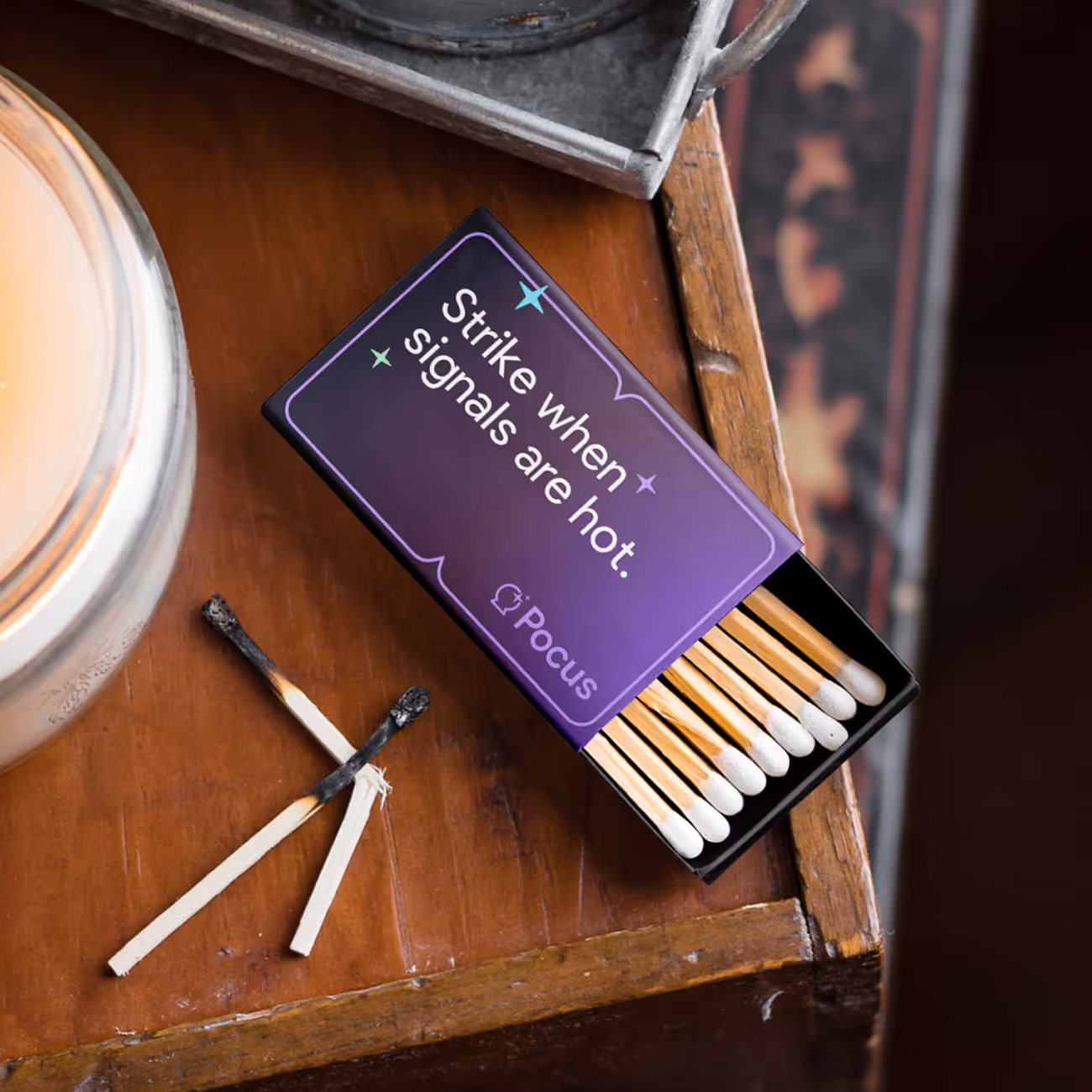 Open box of matches on a wooden surface with the text 'Strike when signals are hot' and two burnt matches crossed nearby.