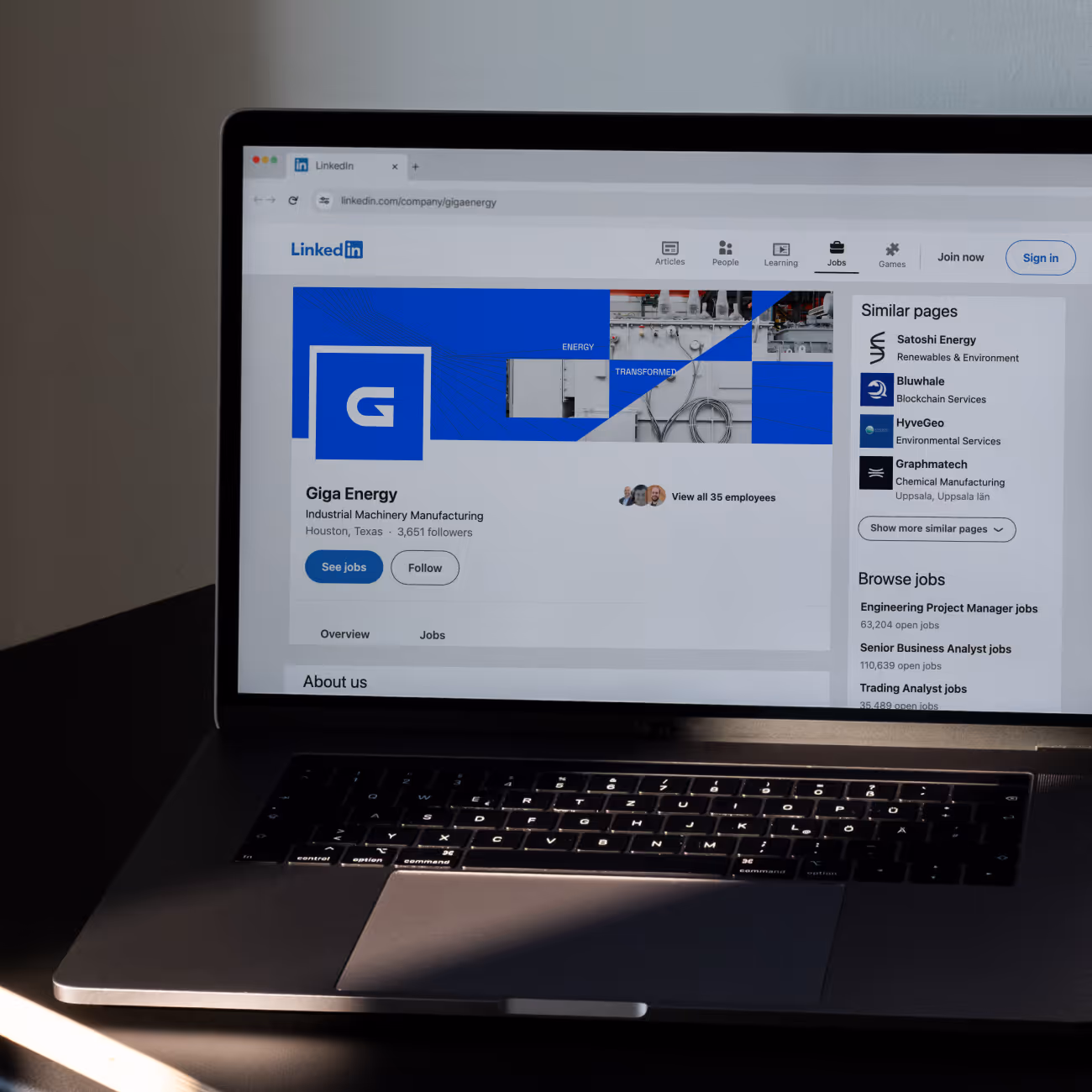 Laptop screen showing Giga Energy LinkedIn page with company info and job listings.