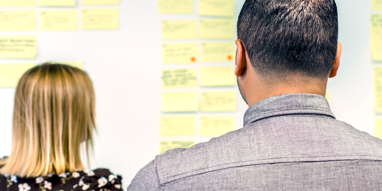 Two members of Marketo's team look over Post-It notes during a strategy on-site.